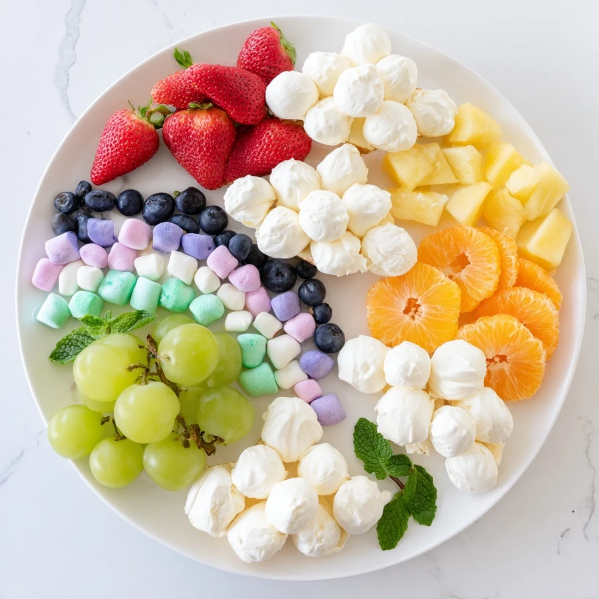 This vibrant Cloud & Rainbow Grazing Board features a rainbow of fresh fruits and creamy cheeses, perfect for celebrations.