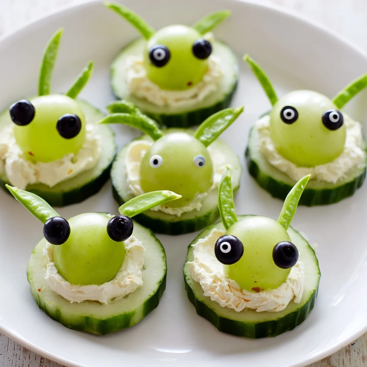 Vibrant Little Green Men Alien Snack Attack on a platter: cucumber faces with grape heads and pretzel antennas.