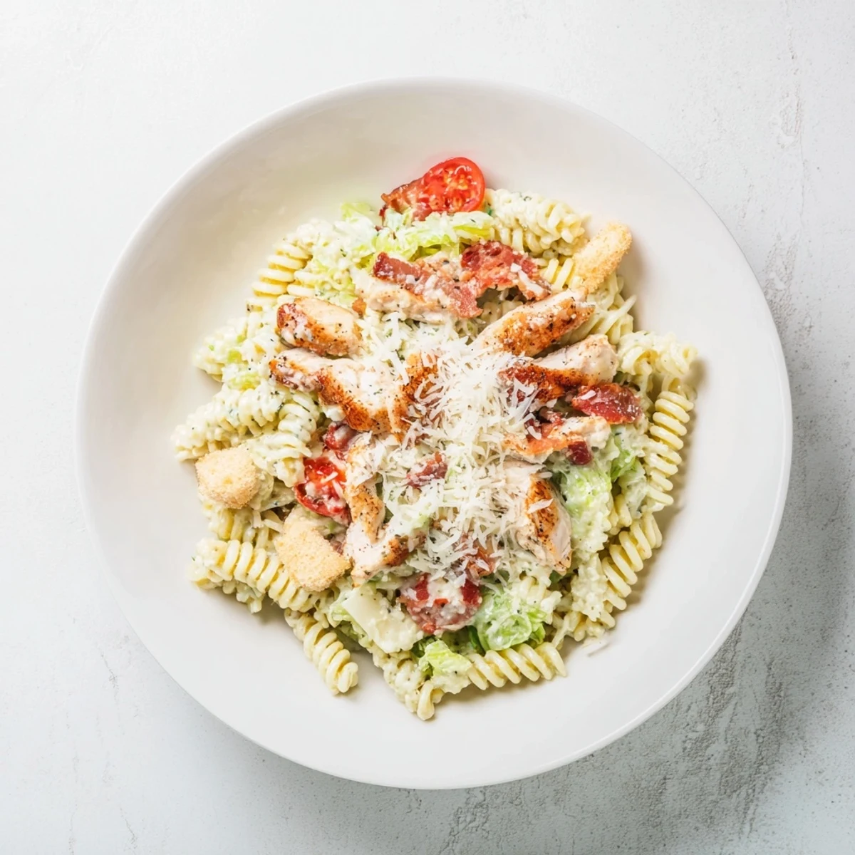 Chicken Caesar Pasta Salad with grilled chicken and crunchy bacon, ready to be tossed.