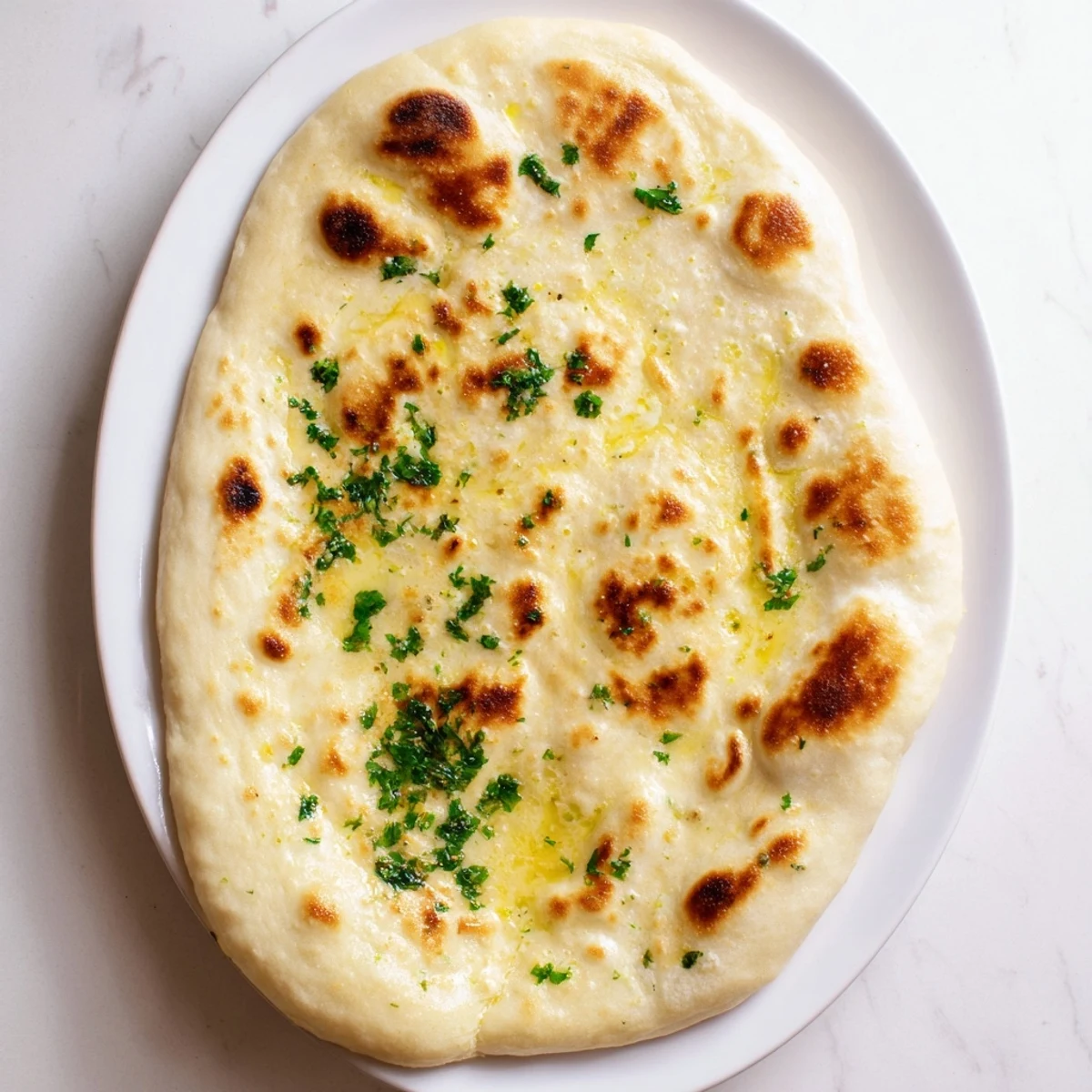Golden-brown homemade garlic naan bread glistening with melted butter, ready for dipping.