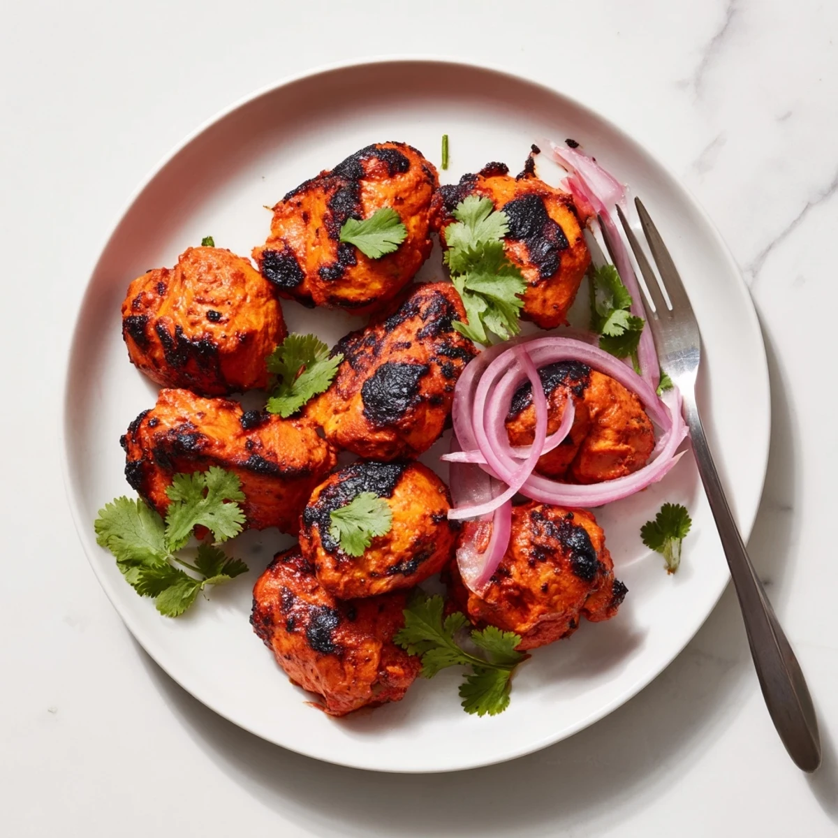 Roasted Indian Tikka Spiced Chicken pieces arranged on a wire rack, glistening with aromatic tandoori spices.