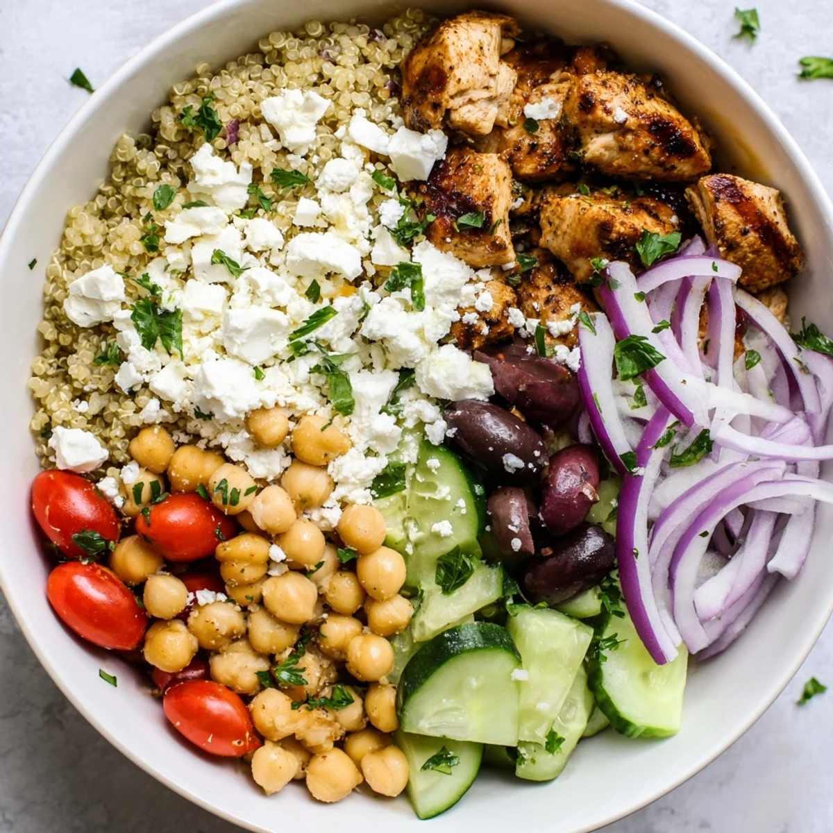 A vibrant Mediterranean Chicken Bowl with juicy grilled chicken, chickpeas, and feta over fluffy quinoa, drizzled with lemon-oregano dressing.