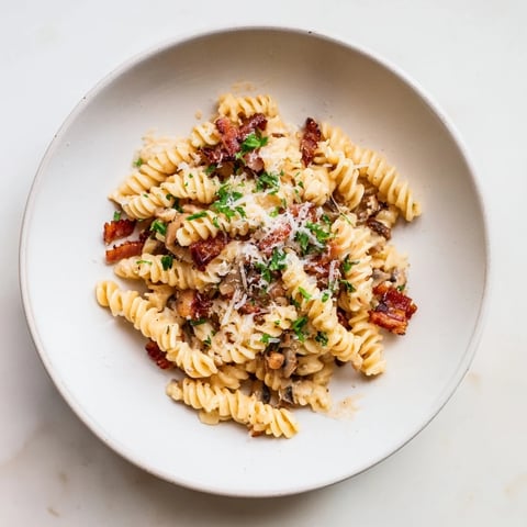 Golden fusilli with bacon, onions, and mushrooms, a comforting Italian pasta dish ready in 30 minutes.