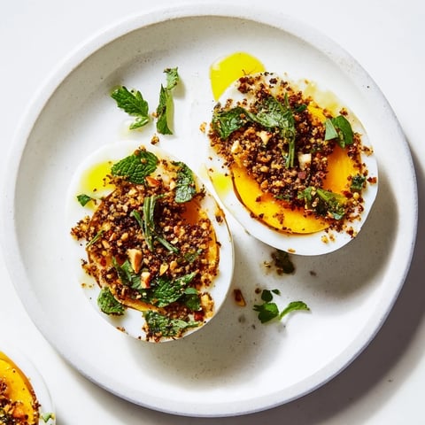 Golden-yolked Dukkah-Spiced Eggs, vibrant with fresh herbs and a satisfying, crunchy dukkah topping.