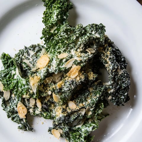 A close-up of vibrant green, massaged kale tossed in creamy garlic-Parmesan dressing, topped with golden toasted breadcrumbs.  