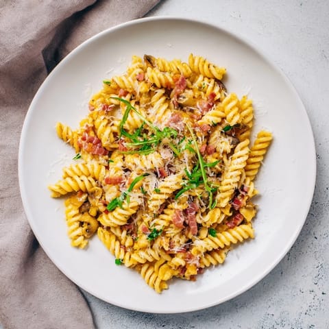 Savory fusilli with bacon, onions and mushrooms, perfectly cooked and tossed with fresh parsley and Parmesan.