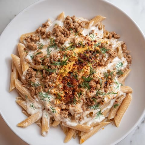 Vivid image of delicious Turkish Pasta with Ground Turkey, creamy yogurt sauce, and a buttery drizzle.
