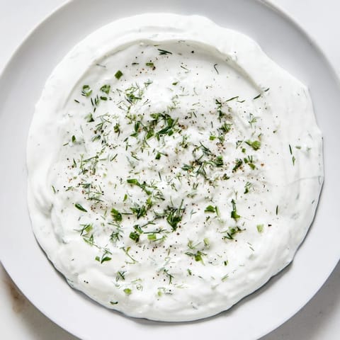 This homemade Greek Yogurt Ranch Dip, speckled with herbs, looks inviting on a serving plate.