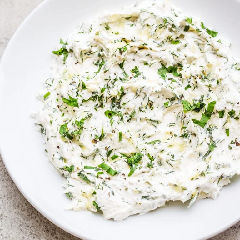 Freshly made Greek Yogurt Herb Dip featuring vibrant green herbs offers a light, savory flavor.