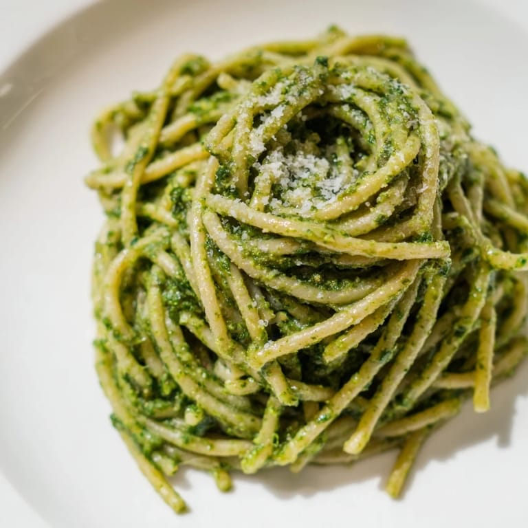 Spoonful of creamy Sunflower Seed Pesto Pasta showing rich, nutty texture with grated Parmesan and a drizzle of olive oil on warm strands.  