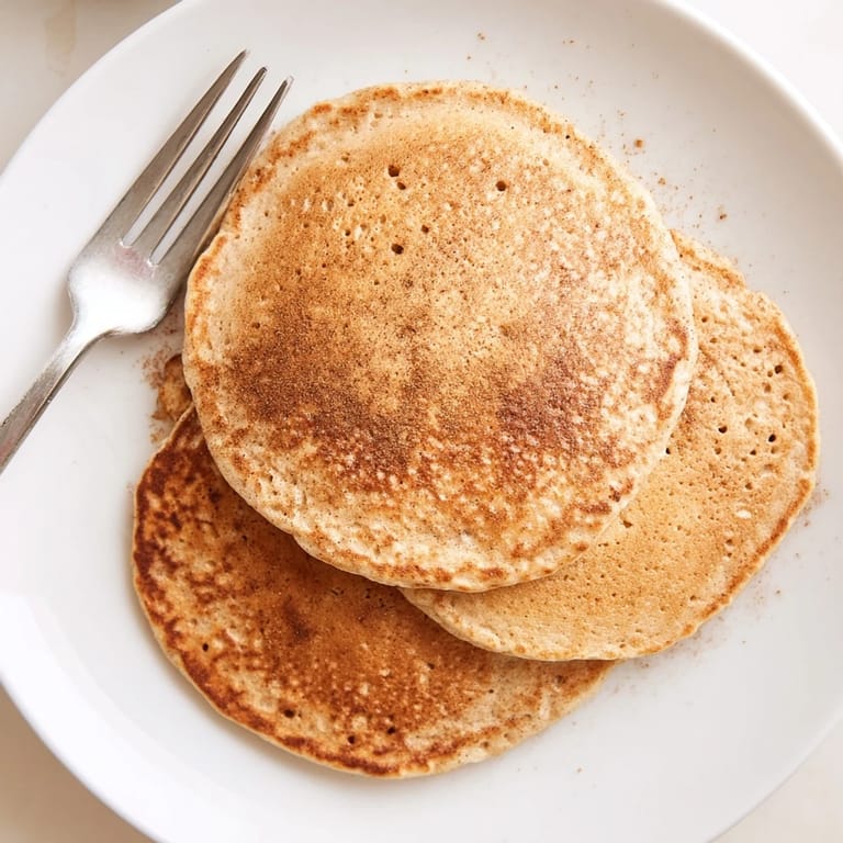 A close-up of freshly cooked Banana Oat Pancakes on a skillet, revealing soft interiors and golden edges, perfect for a weekend morning treat.