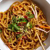 Savory Asian Garlic Noodle Bowl glistening with garlic-butter sauce, topped with green onions and sesame seeds.  