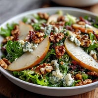 Frisée Pear Blue Cheese Bowl with crisp prosciutto, juicy pear slices, and crunchy walnuts, ready to serve.